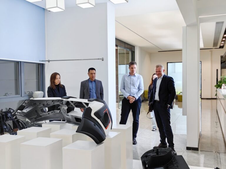 RP Group Limited CEO and founder with executives examining a futuristic automotive interior and exterior parts in the company lobby.